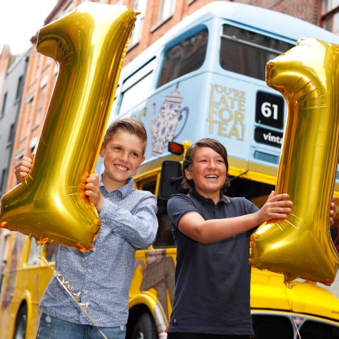 two boys in front of bus with balloons