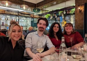 Alejandra Avalos et al. sitting at a table with wine glasses