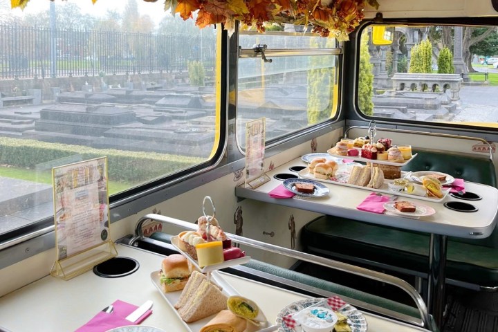 Afternoon tea selection served on tables, with autumn leaves and fairy lights hanging around the bus