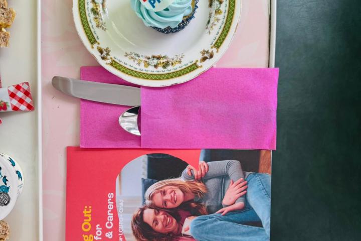 Cupcake with rainbow pride topper on a plate beside a BelongTo booklet.