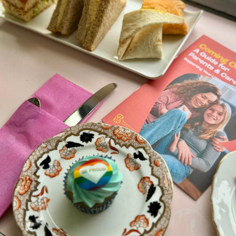 Table with sandwiches, a cupcake, and a brochure for BelongTo beside a window.