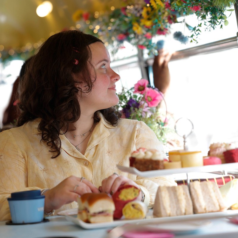 Woman looking out bus window with afternoon tea served in front of her