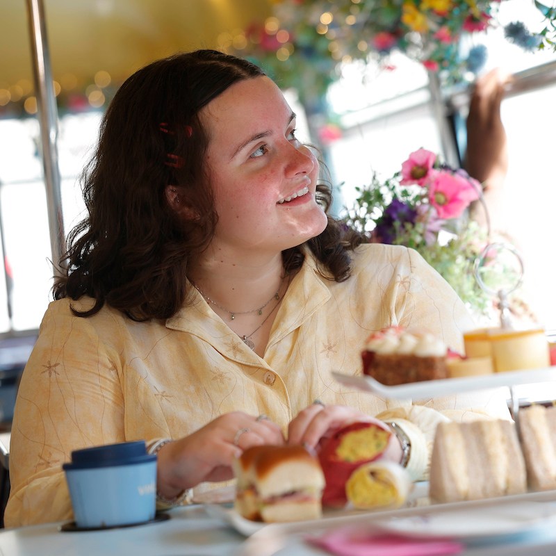 Woman looking out of bus window with afternoon tea served in front of her