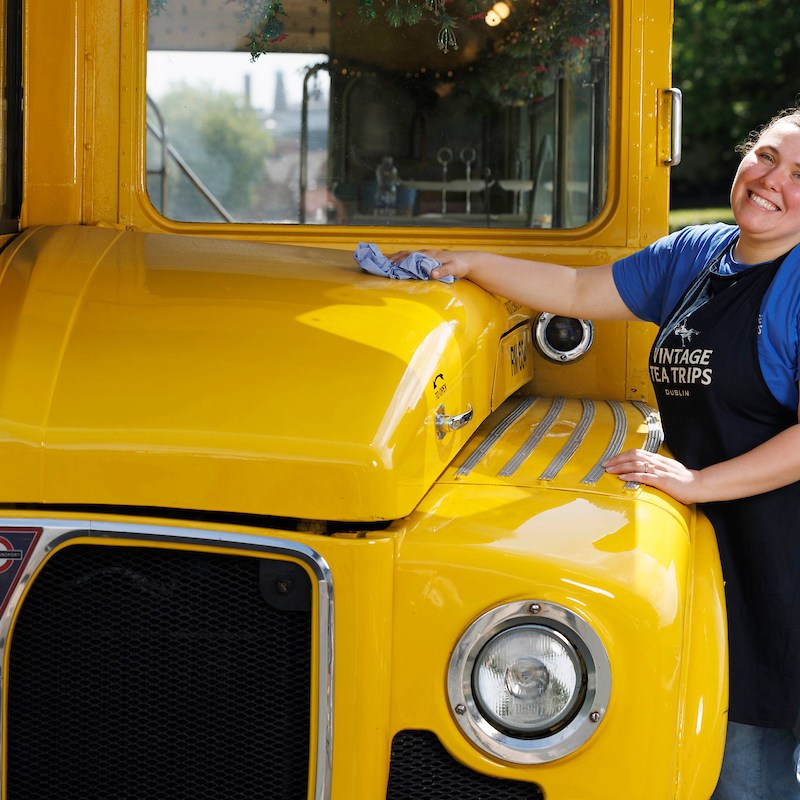 a person standing in front of a school bus parked in a parking lot