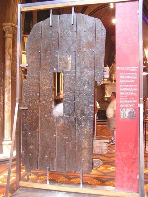 Old wooden door on display with a small rectangular opening, mounted with metal supports.