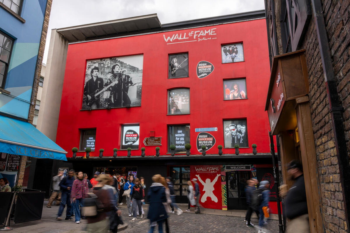 Red building with 'Wall of Fame' featuring musician photos and people walking below on a busy street.