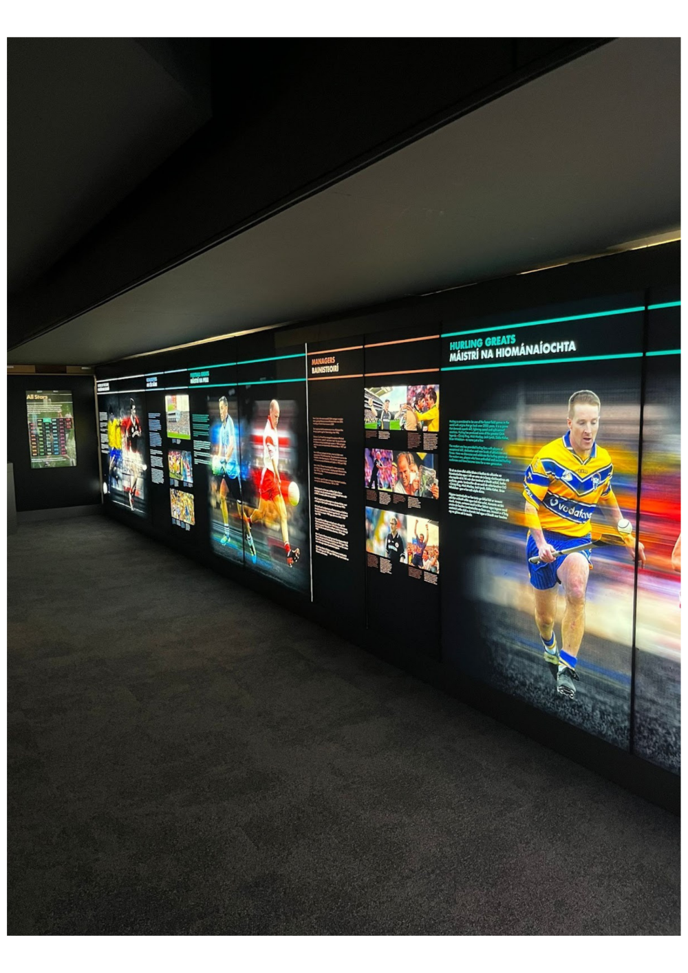 Sports exhibit wall with images and text about hurling greats and managers.