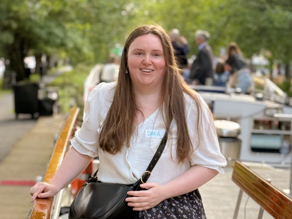 a girl standing on a boat with trees behind