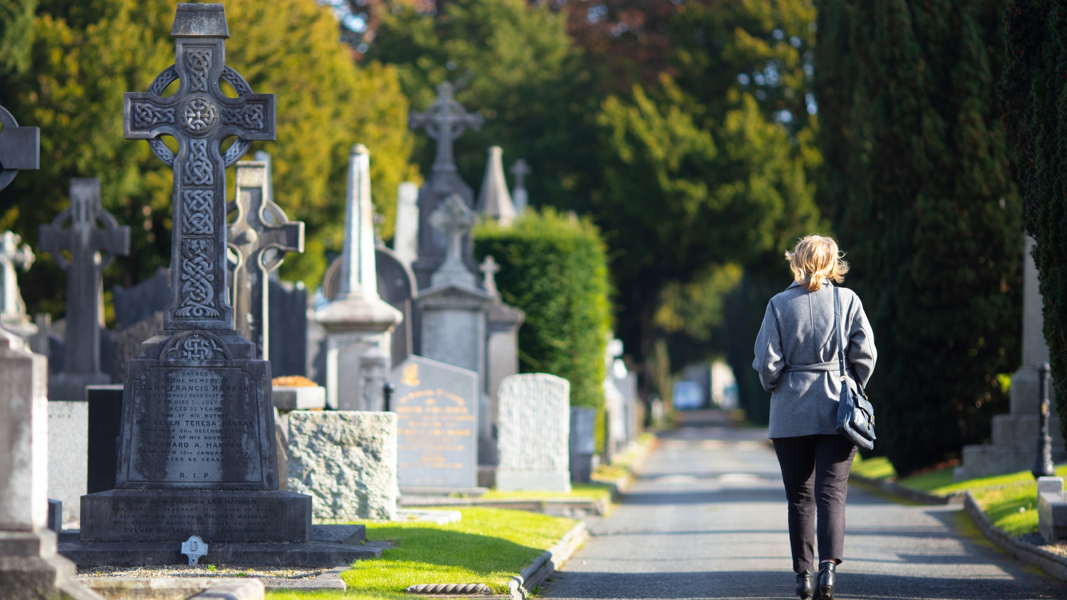 Person walking through a cemetery with various gravestones.