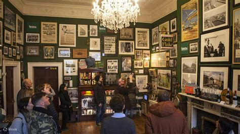 Gallery room with framed photos, chandelier, people observing displays.