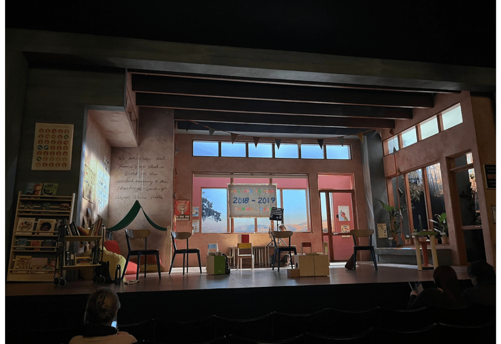 Theater stage set as a classroom with chairs, posters, and a calendar.