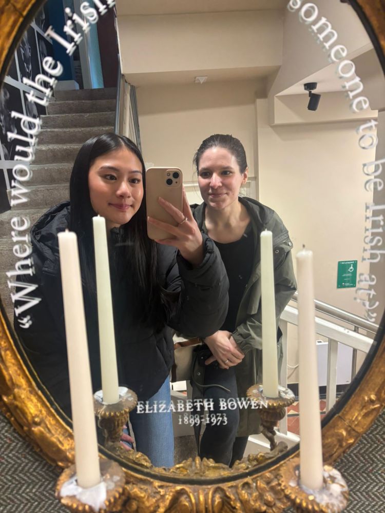 Two people taking a mirror selfie next to a staircase, with candles in the foreground.