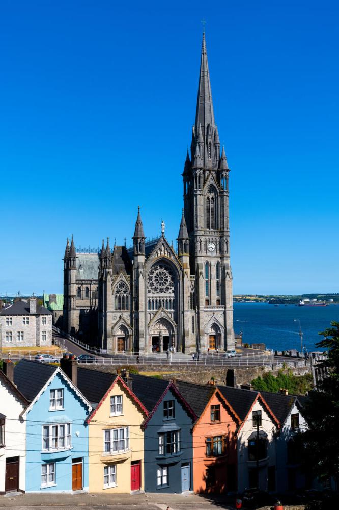 Colorful houses with a large cathedral and ocean in the background.