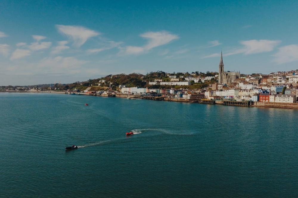 Coastal town with church, houses, and boats on the water.