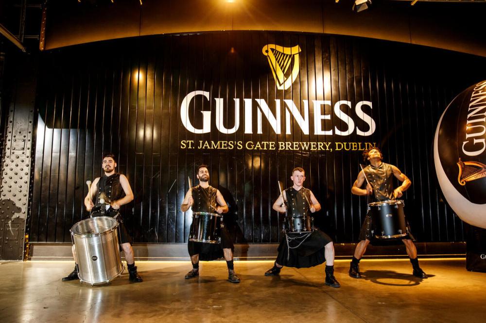 Four drummers perform in front of Guinness sign, St. James's Gate Brewery, Dublin.