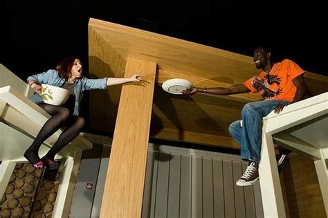 Two people on giant furniture reaching toward each other.
