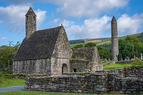 Ancient stone church with round tower in a grassy landscape.