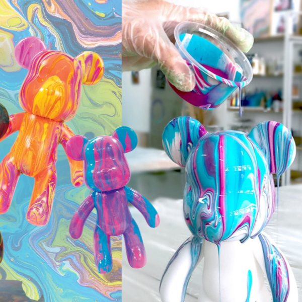 Colorful toy bears with abstract paint design held by gloved hand pouring paint.