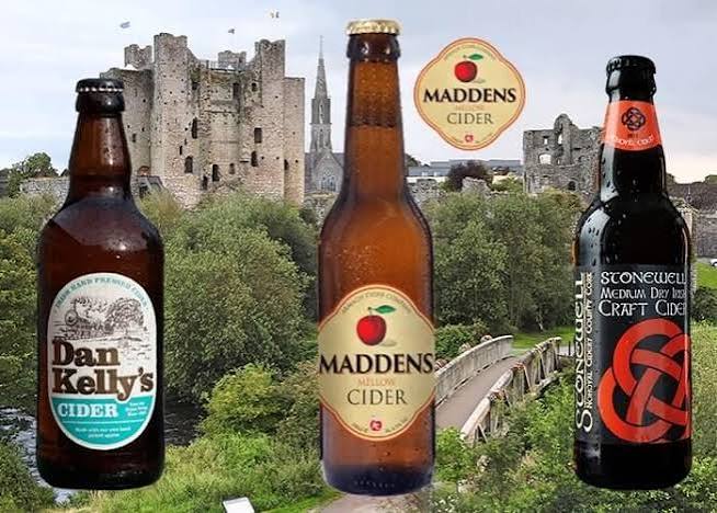 Three cider bottles with castle and greenery background.
